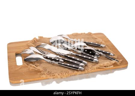 Metal cutlery on a bamboo kitchen board isolated on white background, close-up. Stock Photo