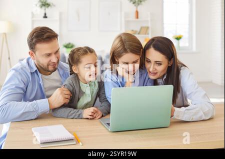 Happy family at laptop online, parents with daughter and son using computer sitting at home, smiling Stock Photo