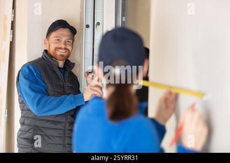 builders measuring a wall using a tape measure Stock Photo