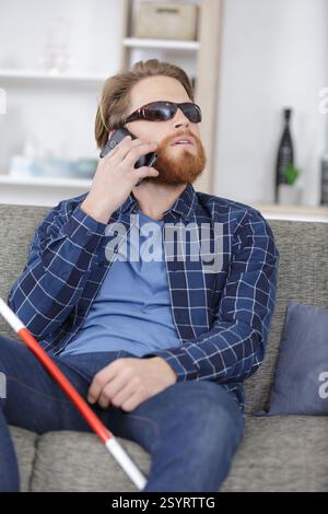 visually impaired man on the sofa using a telephone Stock Photo
