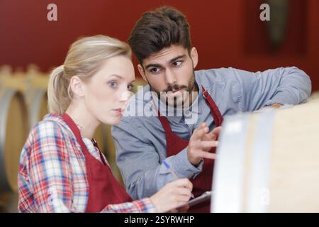 two smiling winery workers in aging section of factory Stock Photo