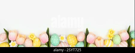 Easter eggs and flower decorations. Top view bottom border against a white banner background. Copy space. Stock Photo