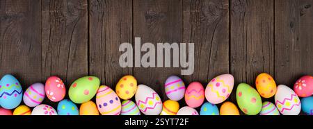 Colorful Easter Egg bottom border over a dark wood banner background. Copy space. Stock Photo