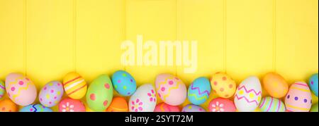 Colorful Easter Egg bottom border over a bright yellow wood banner background. Copy space. Stock Photo