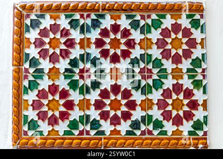 vibrant and intricate tile panel with a geometric pattern in shades of red, green, and yellow, creating a visually stunning and culturally rich decora Stock Photo
