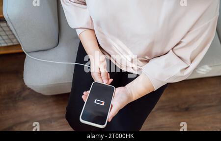 Woman hands Charging mobile phone battery with low battery. plugging a charger in a smart phone  with energy bank powerbank powe Stock Photo