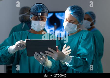 Diverse female surgeons using tablet in operating theatre at hospital Stock Photo
