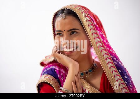 Close-up portrait of a smiling Rajasthani young woman with hand on cheek against white background Stock Photo