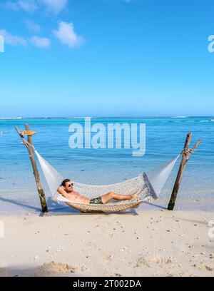 Man relaxing in a hammock on a tropical beach in Mauritius, a man on vacation in Mauritius Stock Photo