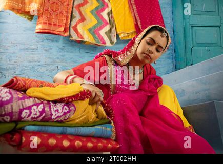 Rajasthani woman selling colourful local fabrics outside her house in Rajasthan Stock Photo