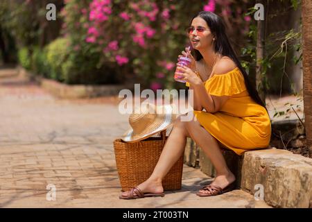Woman drinking detox water while sitting in the park Stock Photo