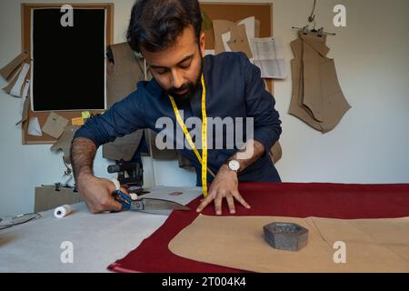 Male designer cutting fabric for a jacket in his studio Stock Photo