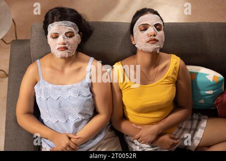 To angle view of two women with facial mask relaxing on sofa Stock Photo