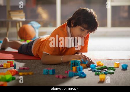 Boy playing with toy blocks while lying on floor Stock Photo