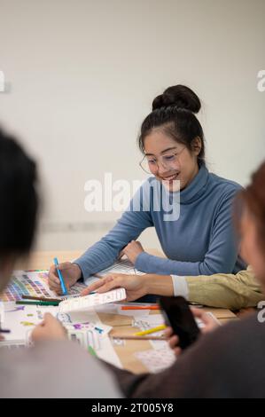 Young smart Asian UI/UX designer working for the project with her team in the meeting room. UX/UI concept. Stock Photo