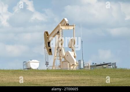 A crude oil production well, a site with a pump jack in a rural area during summer in Alberta Canada. Concept: Oil And Gas Compa Stock Photo