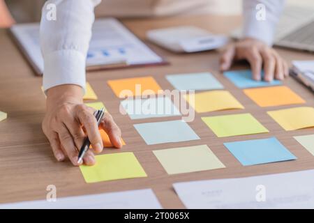 Business People working on sticky notes creative writing down ideas on post it notes professional investor start up project busi Stock Photo