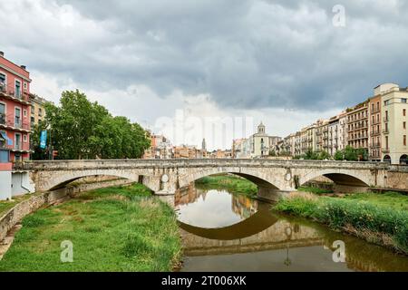 Colorful yellow and orange houses and bridge Pont de Sant Agusti reflected in water river Onyar, in Girona, Catalonia, Spain. Ch Stock Photo