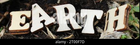 nature wooden letters in the sun on a sunny happy day.  create word text from wooden letter alphabet. naturally wood background, letters EARTH Stock Photo