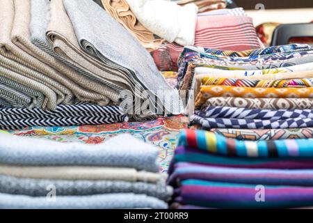 Various fabrics folded on a table with different patterns, materials and colors for sale Stock Photo