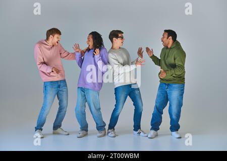 four cheerful surprised men in bright urban attires looking at each other, cultural diversity Stock Photo