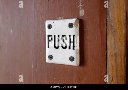 old porcelain push sign on brown door Stock Photo