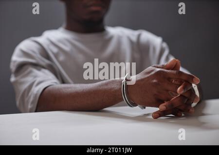 Close up of Black young man wearing handcuffs as arrested criminal, copy space Stock Photo