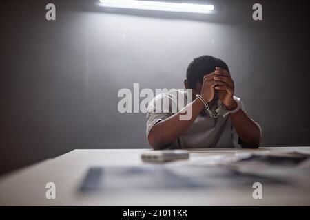 Minimal portrait of Black young man wearing handcuffs crying in remorse as criminal arrested, copy space Stock Photo