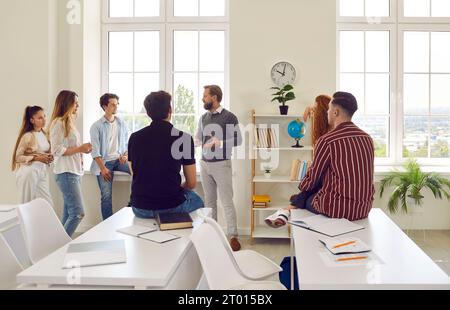 Professor is talking with group of students in audience during break between lections in college. Stock Photo