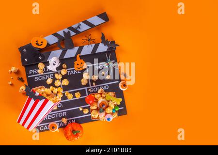 Horror movie, series night, Halloween cinema party with trick-or-treating sweets bucket, popcorn, movie clapperboard and Halloween decorations on high Stock Photo