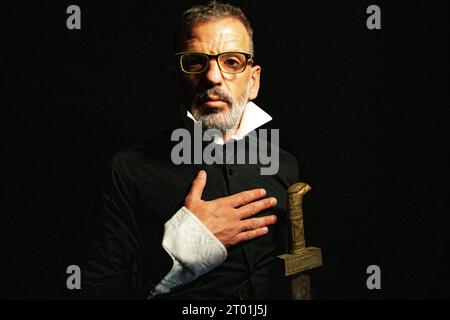 Man dressed in black and white collar with serious gesture that looks like the man from El Greco's Knight of the Hand on the Chest on a black backgrou Stock Photo