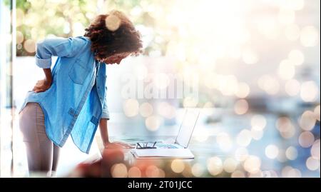 Laptop, backache and posture with a business woman holding her spine in pain at the office for work. Computer, space and a young design employee Stock Photo