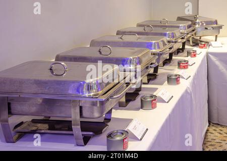 Chaffing dishes arranged in a row on tables in a hotel ready to serve food at a self service buffet at a party Stock Photo