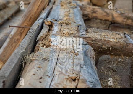 Old, damaged wooden beams lie with rusty nails stuck in after the demolition of the barn. Barn. Stock Photo