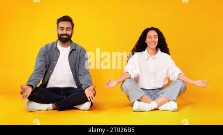 Arabic Couple Meditating Sitting In Lotus Pose Over Yellow Background Stock Photo