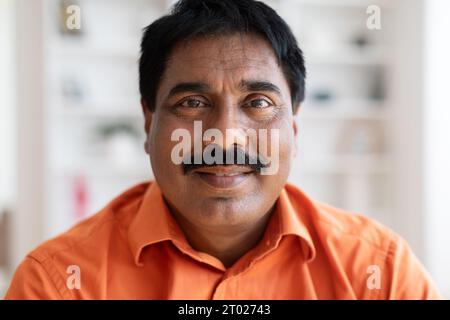 Closeup portrait of middle aged indian man wearing orange shirt Stock Photo