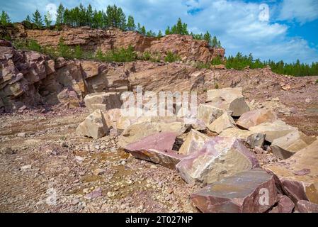 Blocks of crimson quartzite in an abandoned quarry. Karelia, Russia Stock Photo