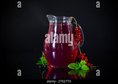 Cold refreshing drink from fresh summer berries in a decanter, isolated on a black background. Stock Photo