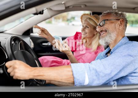 Happy elderly spouses having car trip together, using smartphone gps Stock Photo