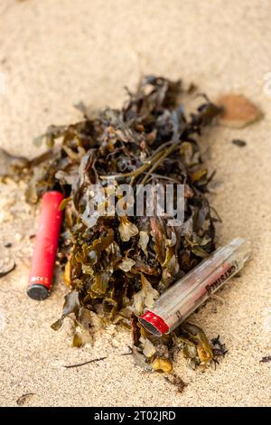 Single use disposable vapes lying discarded on a beach Stock Photo