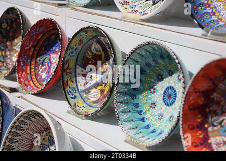 Rows of beautiful multicoloured decorative Bowls of various designs of repetitive and Floral patterns, displayed on White Shelves, seen from the side Stock Photo