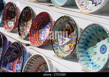 Rows of beautiful multicoloured decorative Bowls of various designs of repetitive and Floral patterns, displayed on White Shelves, seen from the side Stock Photo