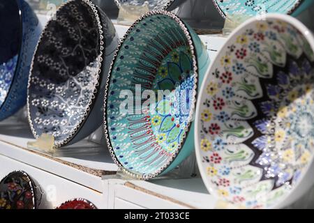 Rows of beautiful multicoloured decorative Bowls of various designs of repetitive and Floral patterns, displayed on White Shelves, seen from the side Stock Photo