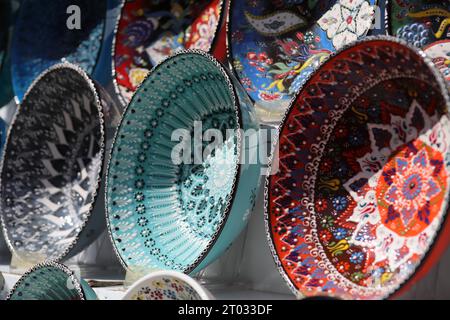 Rows of beautiful multicoloured decorative Bowls of various designs of repetitive and Floral patterns, displayed on White Shelves, seen from the side Stock Photo