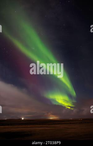 During wintertime, famous northern lights spotted over hills covered with snow. Icelandic magical aurora borealis create incredible show that brighten up cold night sky with stars. Stock Photo