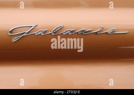 “Galaxie “ - a chrome cast alloy script badge insignia embellishing the rear quarter panel on a 1959 Ford Fairlane 500 Galaxie Skyliner, July 2022. Stock Photo