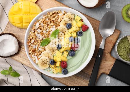 Tasty matcha smoothie bowl with fresh fruits and oatmeal served on grey table, flat lay. Healthy breakfast Stock Photo