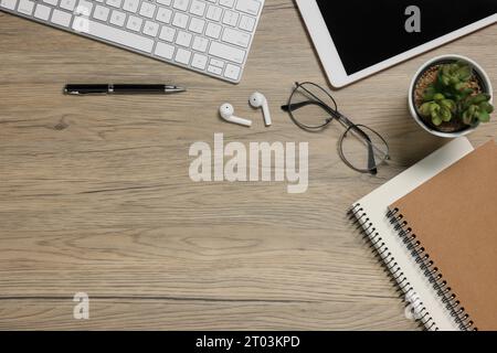 Flat lay composition with computer keyboard and different stationery on wooden desk, space for text. Home office Stock Photo