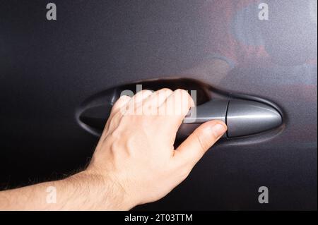 Hand hold car door handle gray metallic color close up view Stock Photo