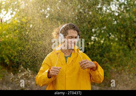 Young arabic man dancing in the field and listening music in headphones. Sunshine on attractive guy enjoying a summer rain. Stock Photo